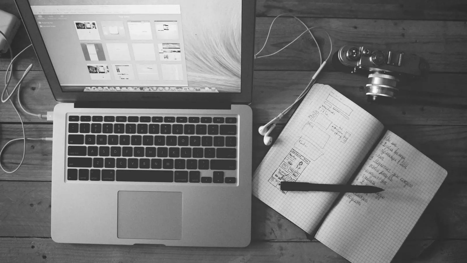 A laptop next to an open notebook filled with handwritten notes