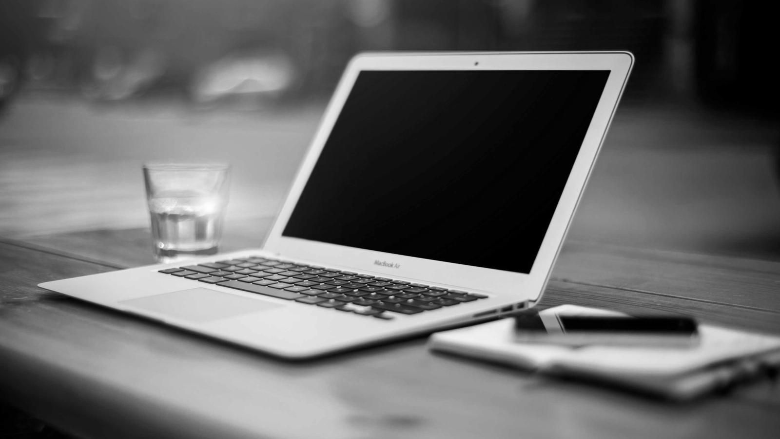 An open laptop and a notebook on a wooden table