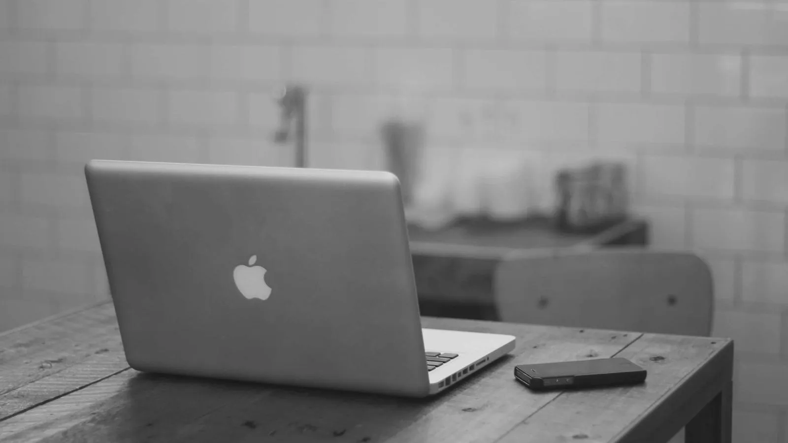 A laptop on a wooden desk in a bright, tiled room