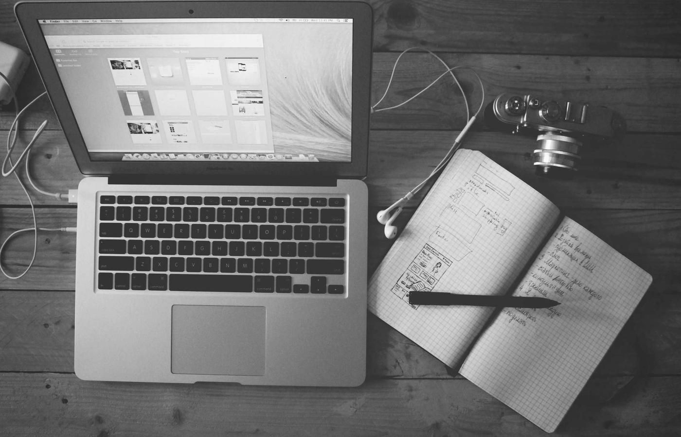 A laptop showing design work beside a notebook of sketches